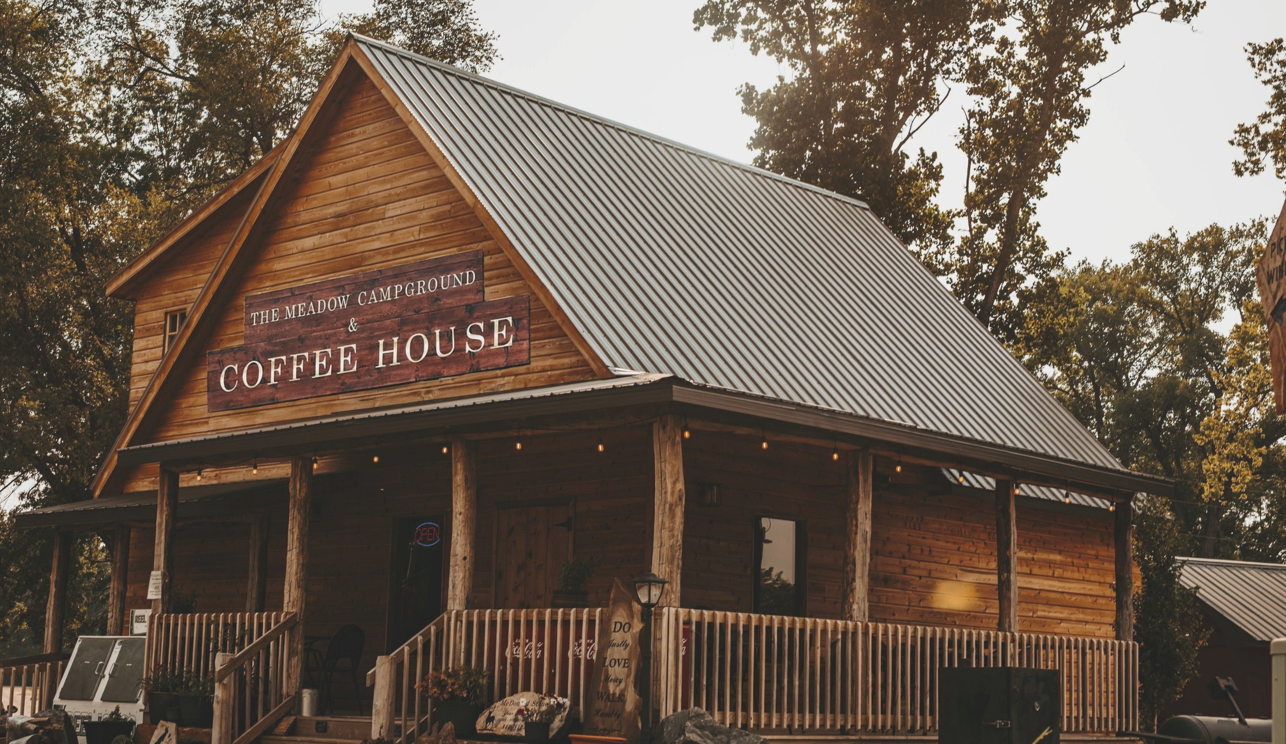 A log cabin style coffee shop on a campground, the sign states 'The Meadow Campground & Coffee House'
